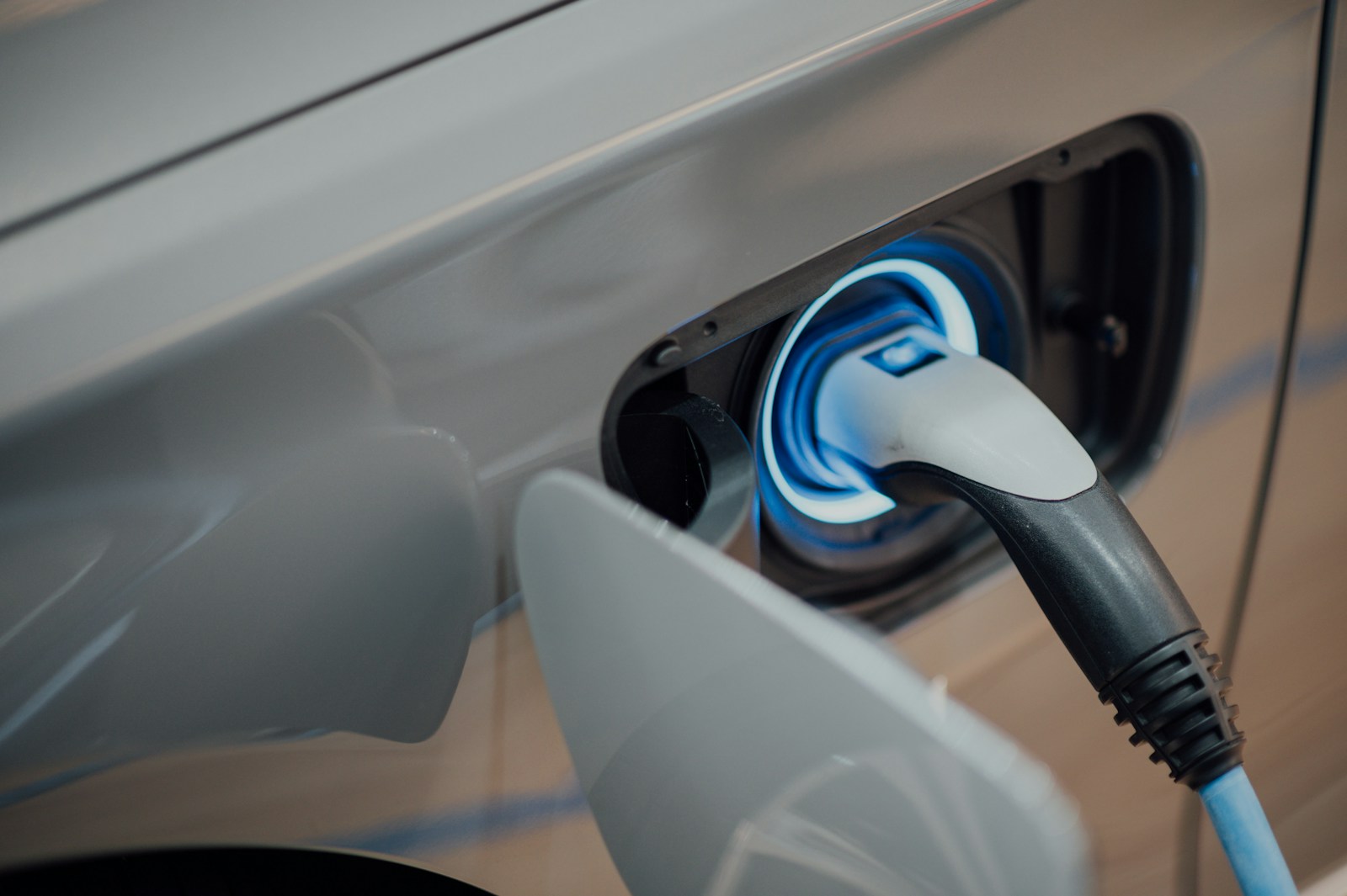 electric car charger plugged into pale grey car