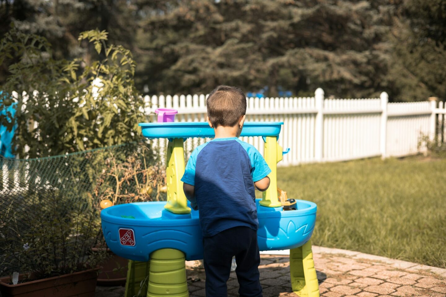 a young boy playing in a blue and yellow water table in garden