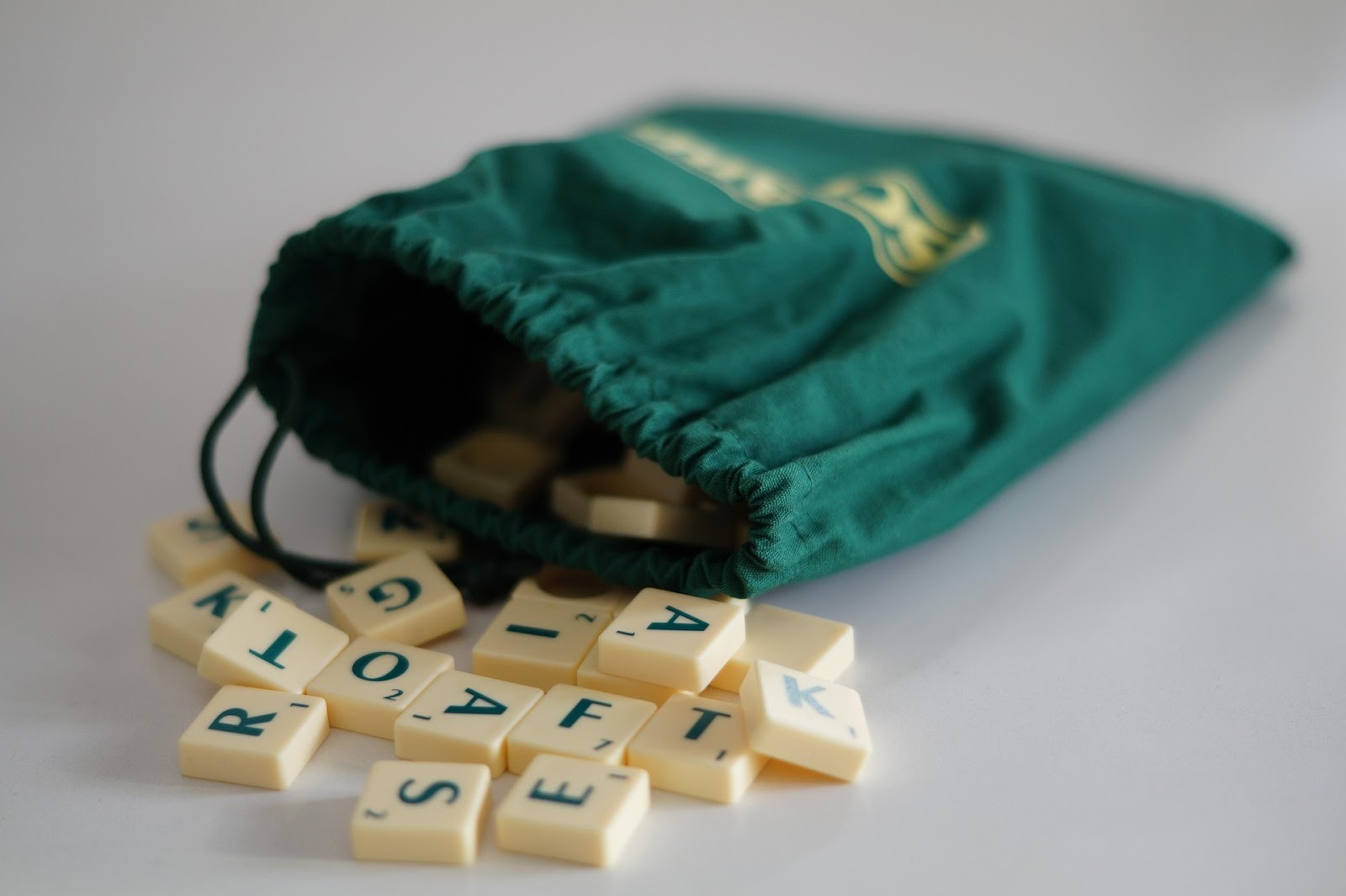 green scrabble bag with pieces coming out of it