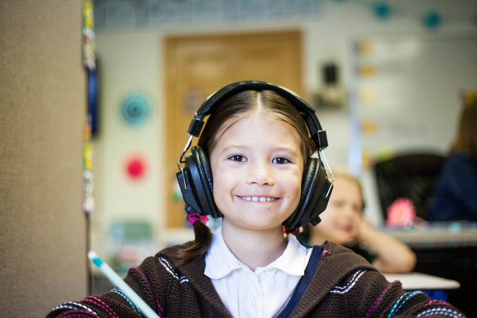 girl wearing black headphones in school and smiling
