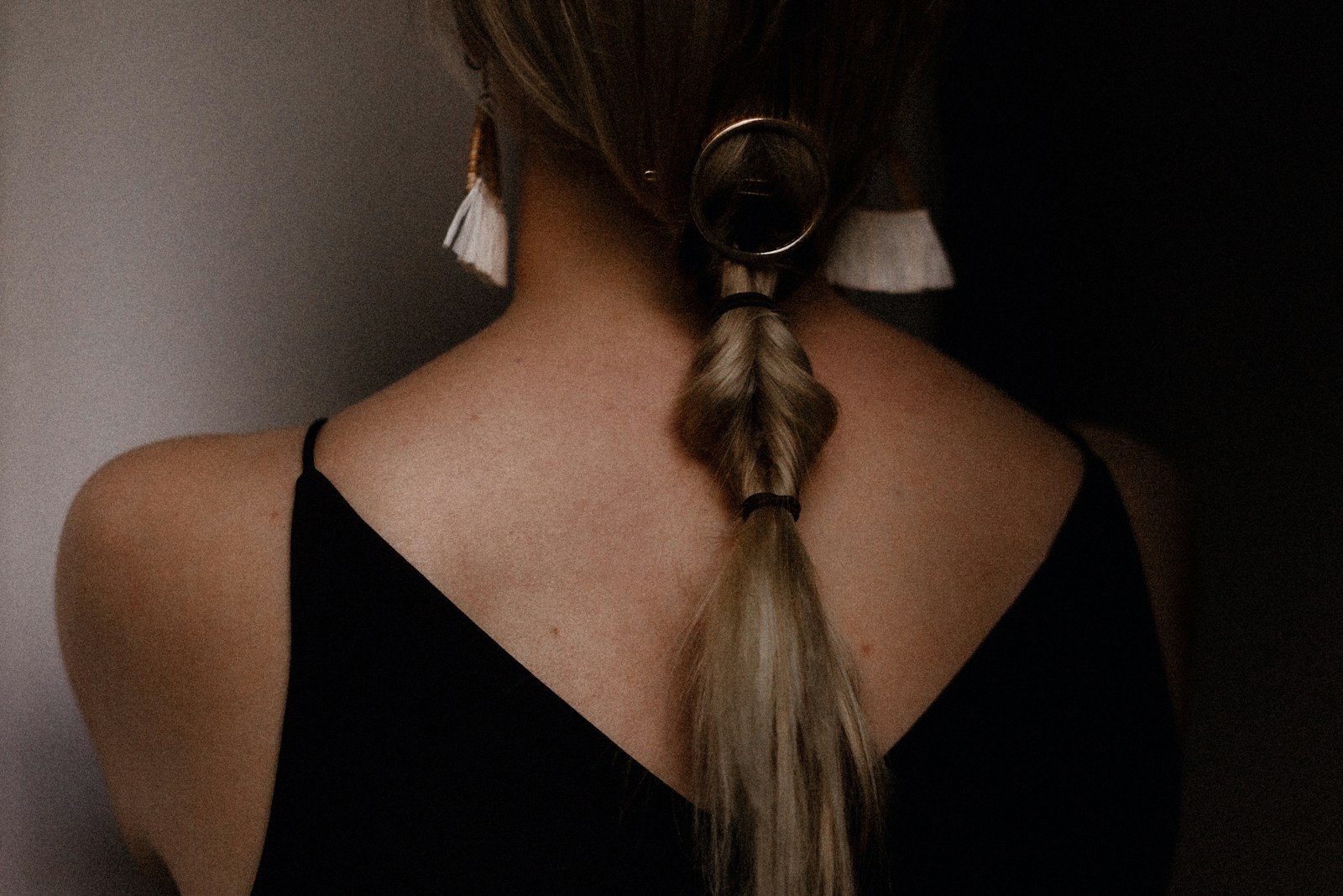 woman from the back, in black tank top wearing dangly earrings
