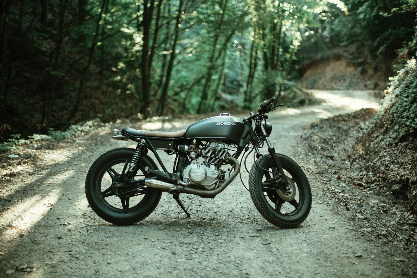 motorcycle parked on road between trees