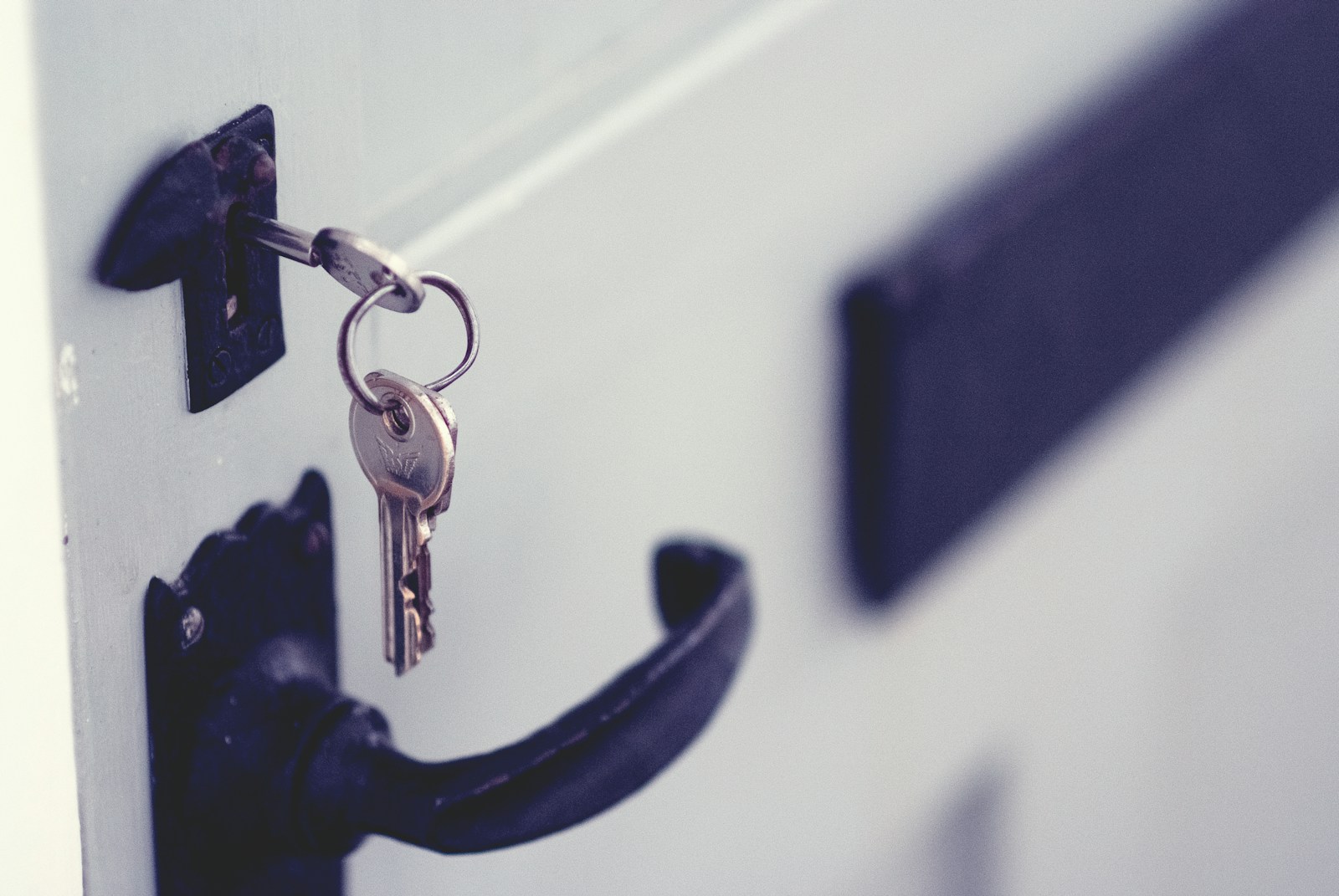 key hanging in white door with black handle and letterbox