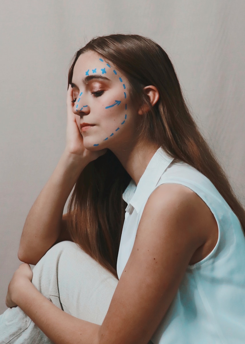woman in white sleeveless shirt with blue eyes with drawn-in arrows on face