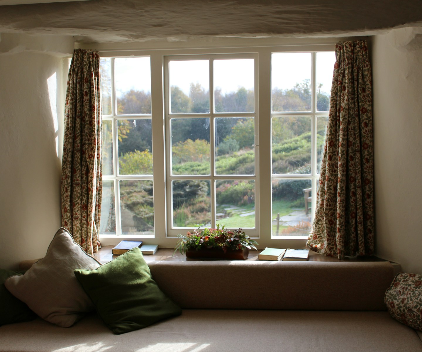 window with curtains and hanging and flowers and cushiosn in front of it