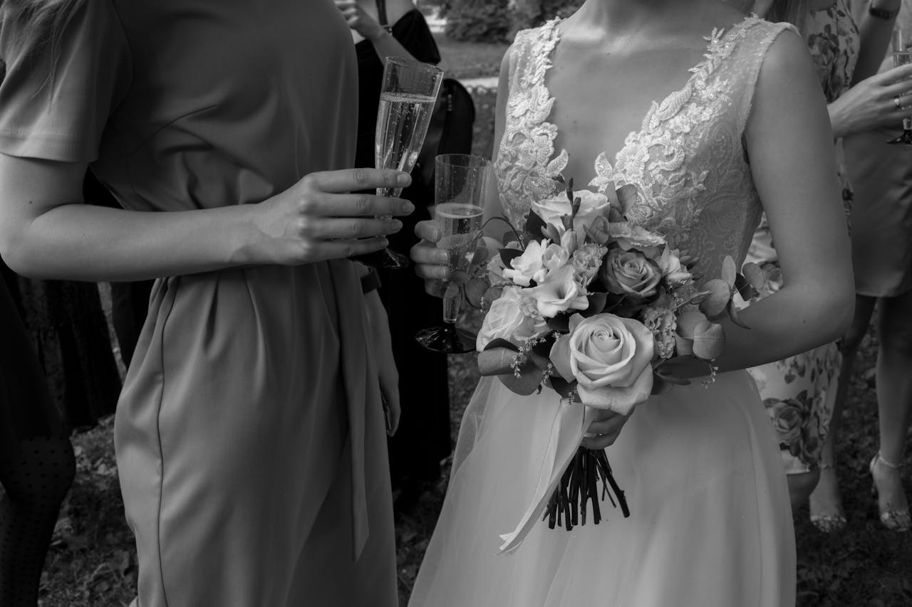 black and white shot of bride and guest standing next to each other and bride holding bouquet