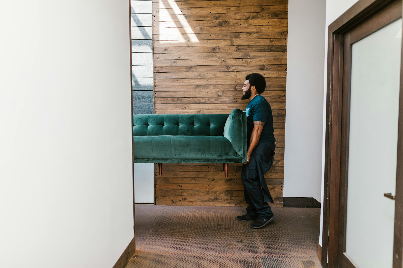 man with beard holding one end of green sofa in the air