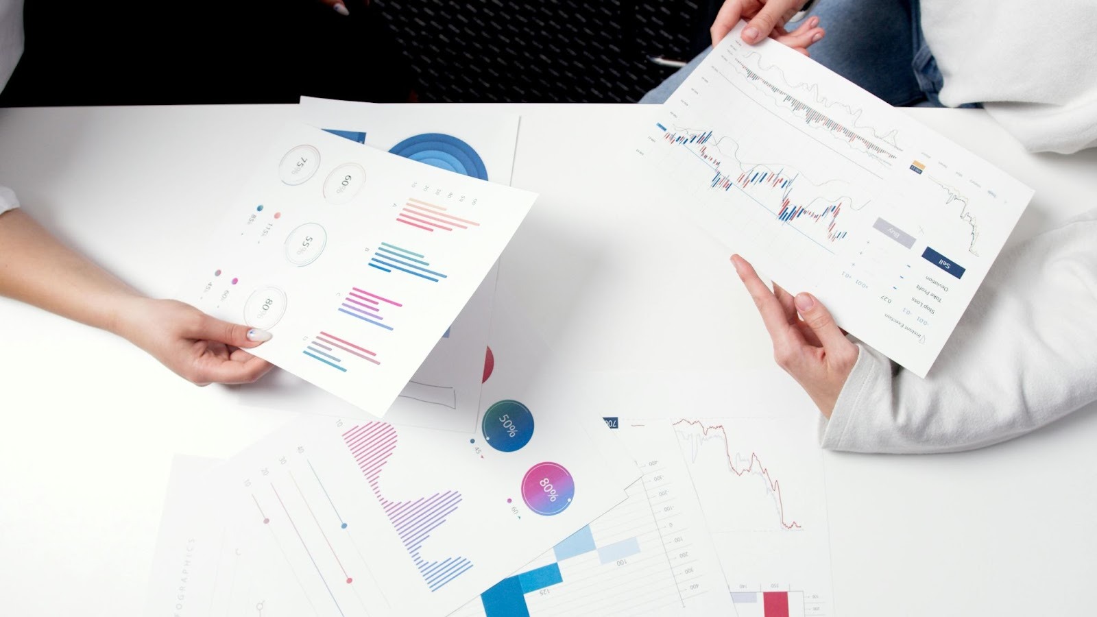 two people holding onto pieces of paper with graphs and charts on