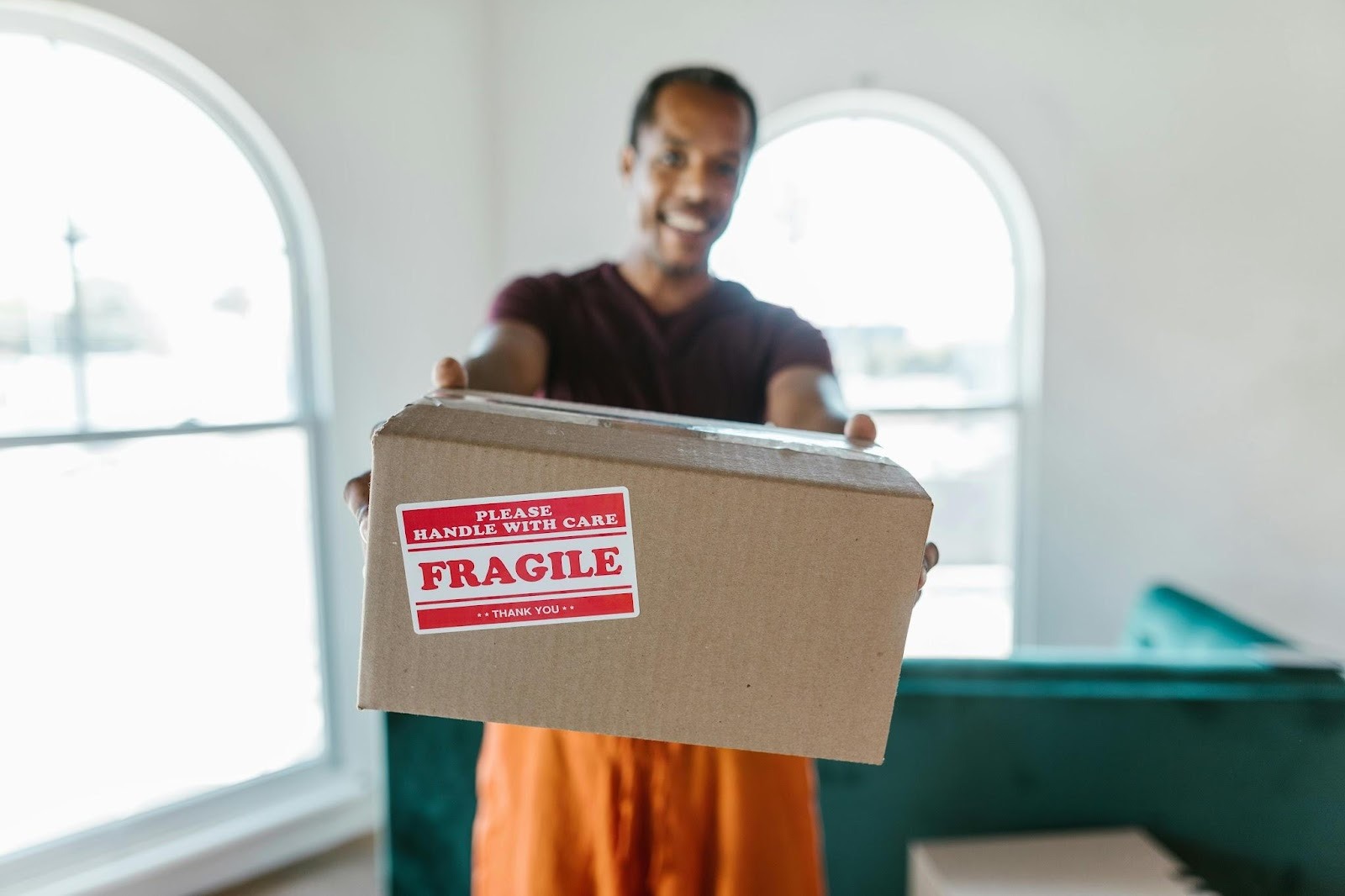 man smiling and holding packing box with fragile sticker on it