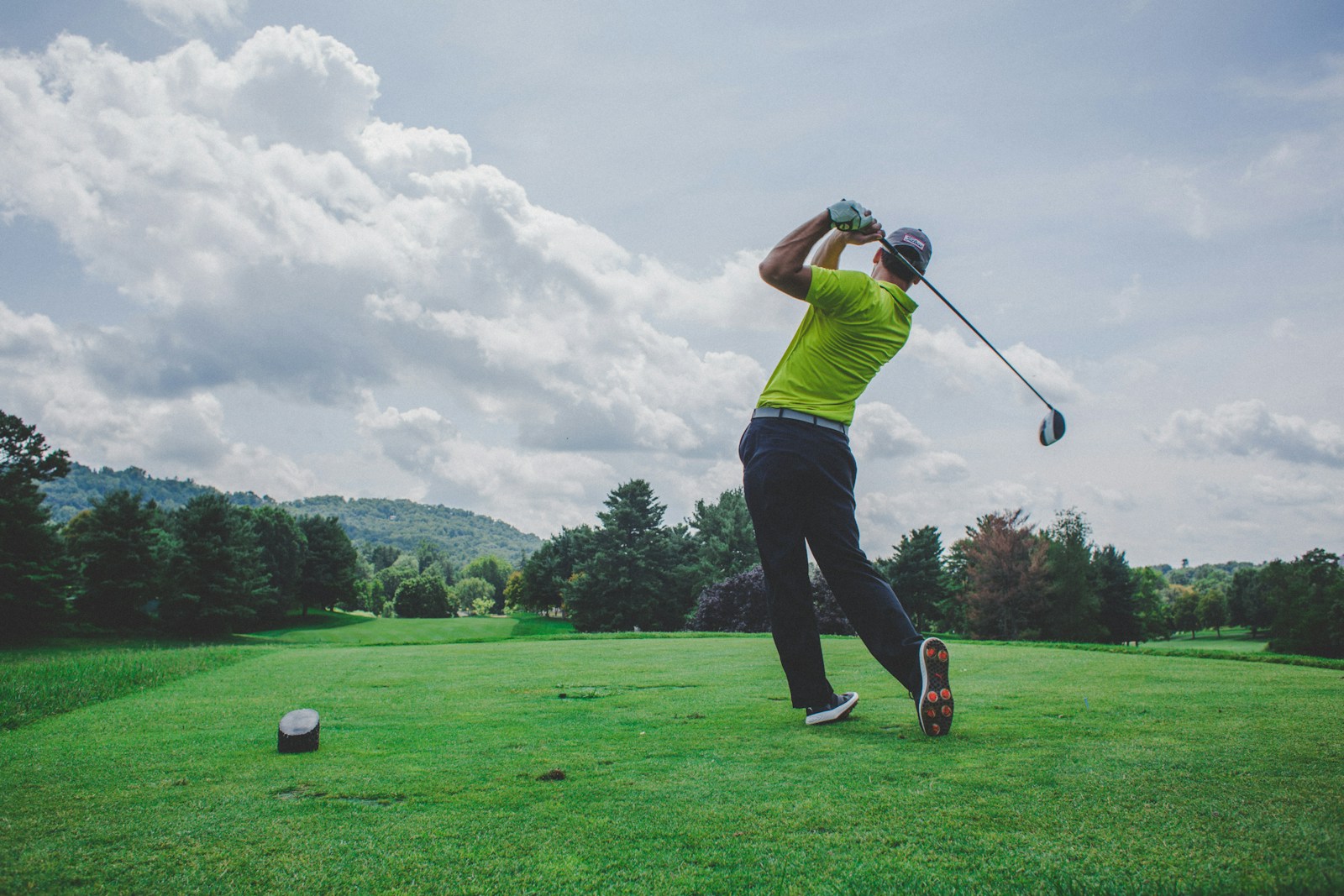 photo of man swinging golf driver on gold course