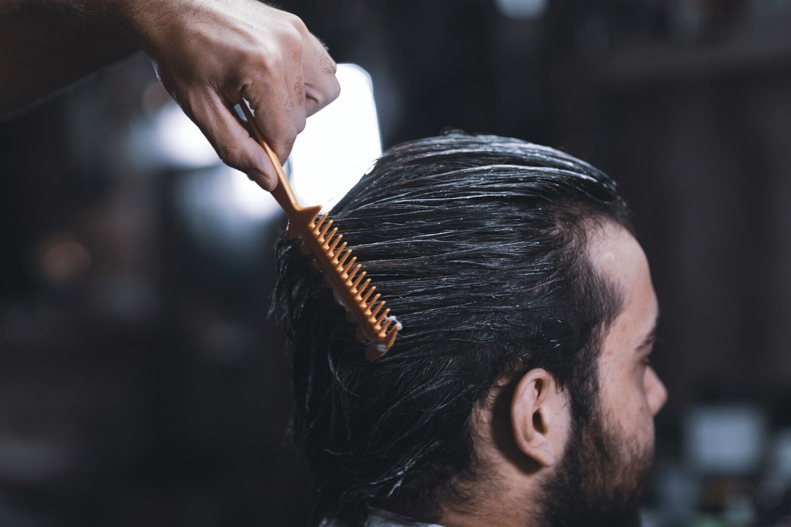 man with long hair and beard with person brushing their hair