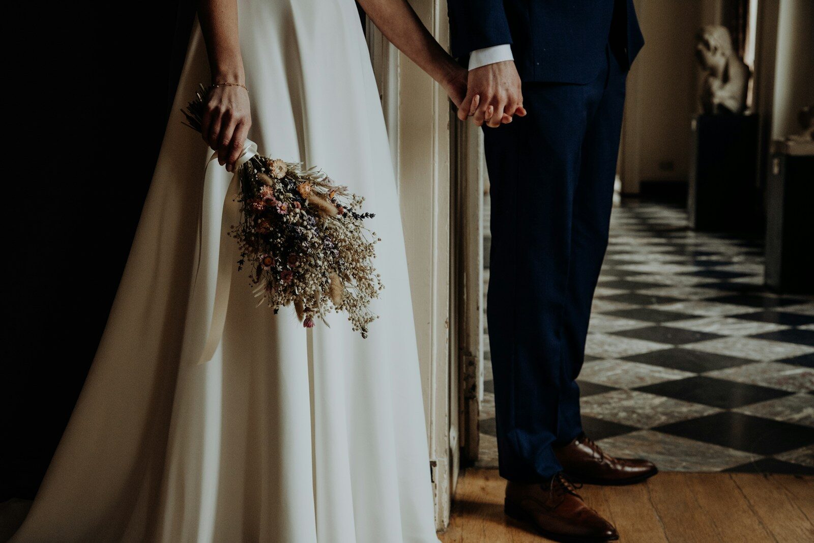 man in black suit holding woman in white dress's hand at wedding