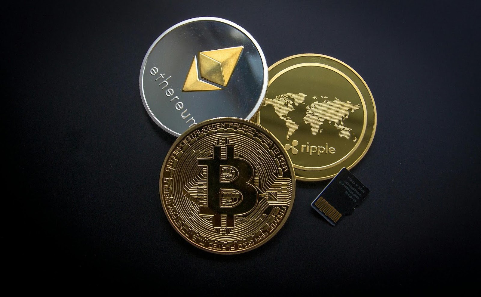three cryptocurrency coins on black background