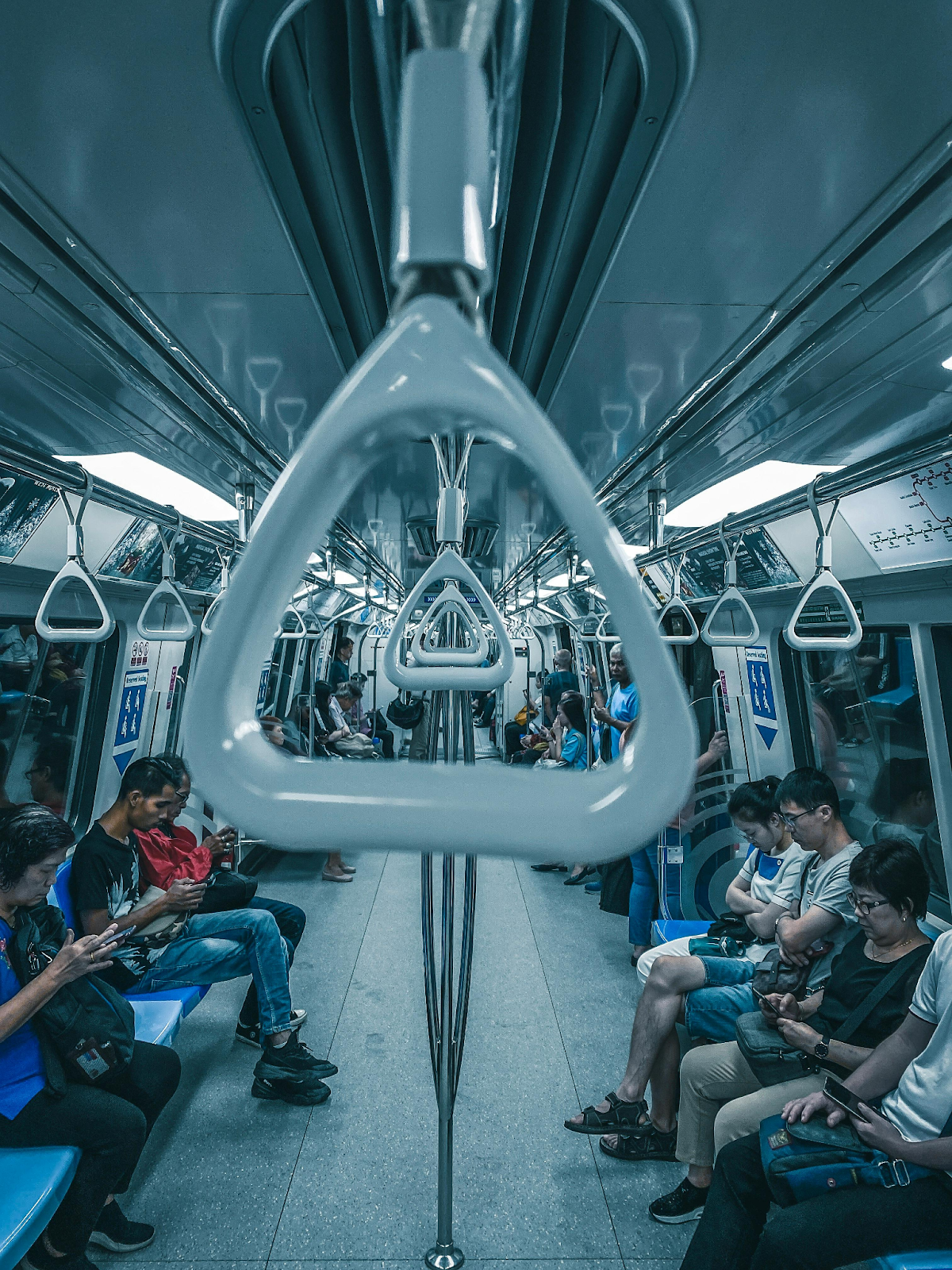 people seated along either side of a tube, some looking at their phones