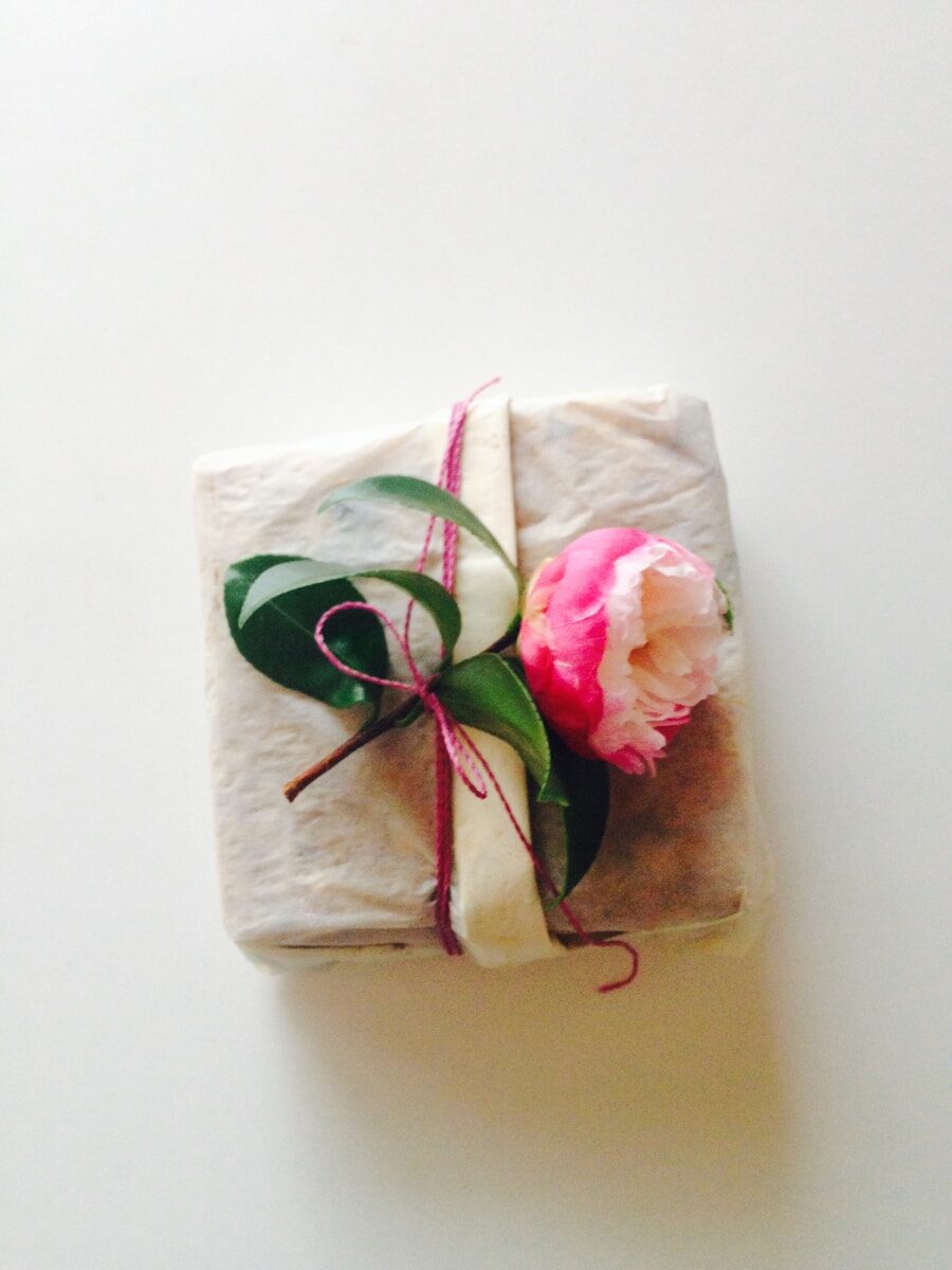 white and pink floral textile-wrapped present with flower in it