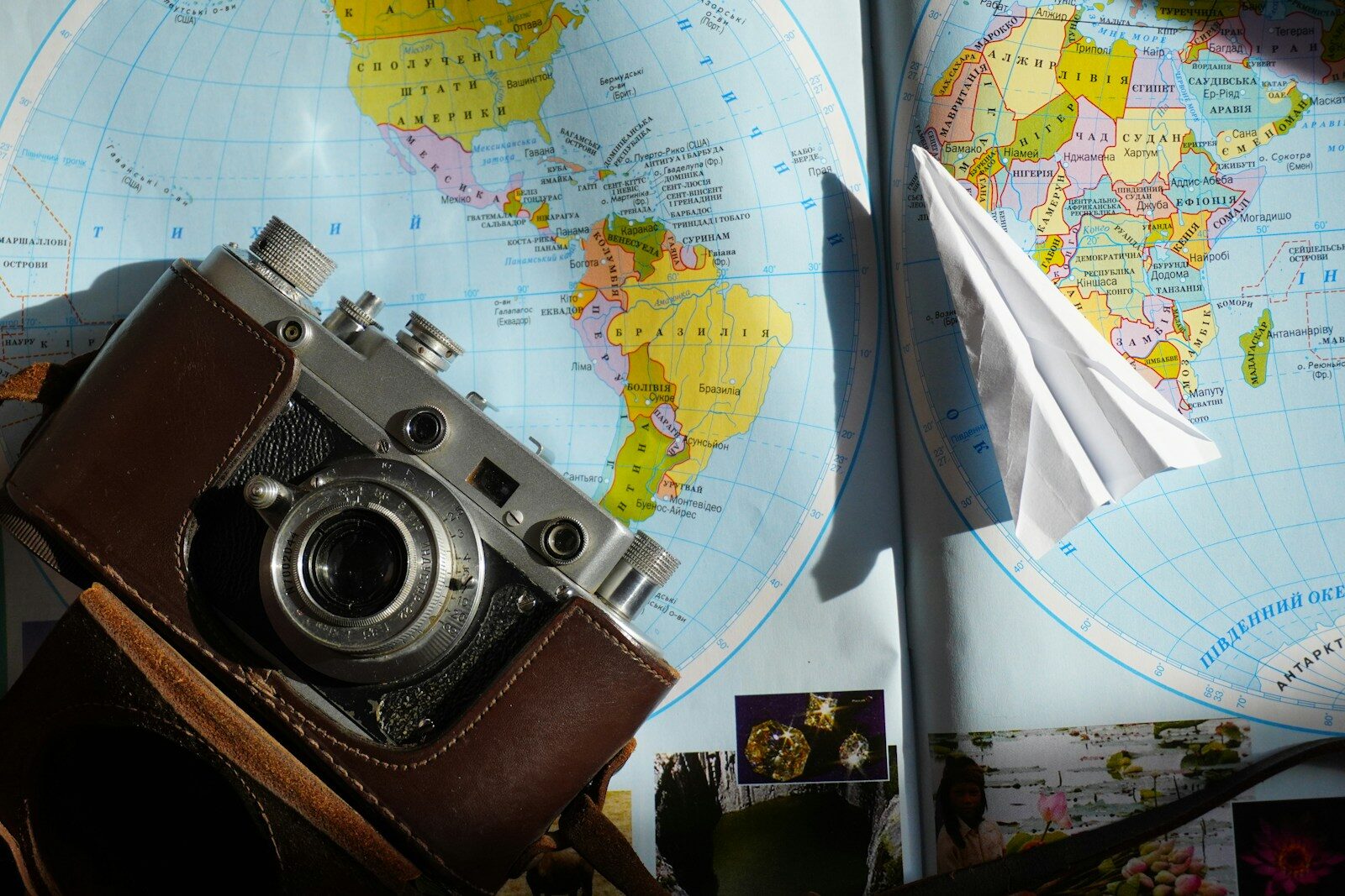 Vintage camera and paper aeroplane on world map.