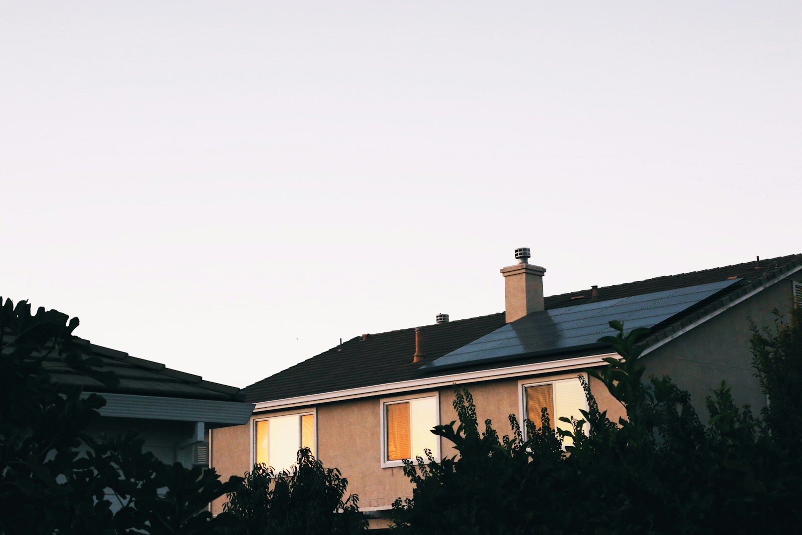 house with solar panels on the roof, mext to trees