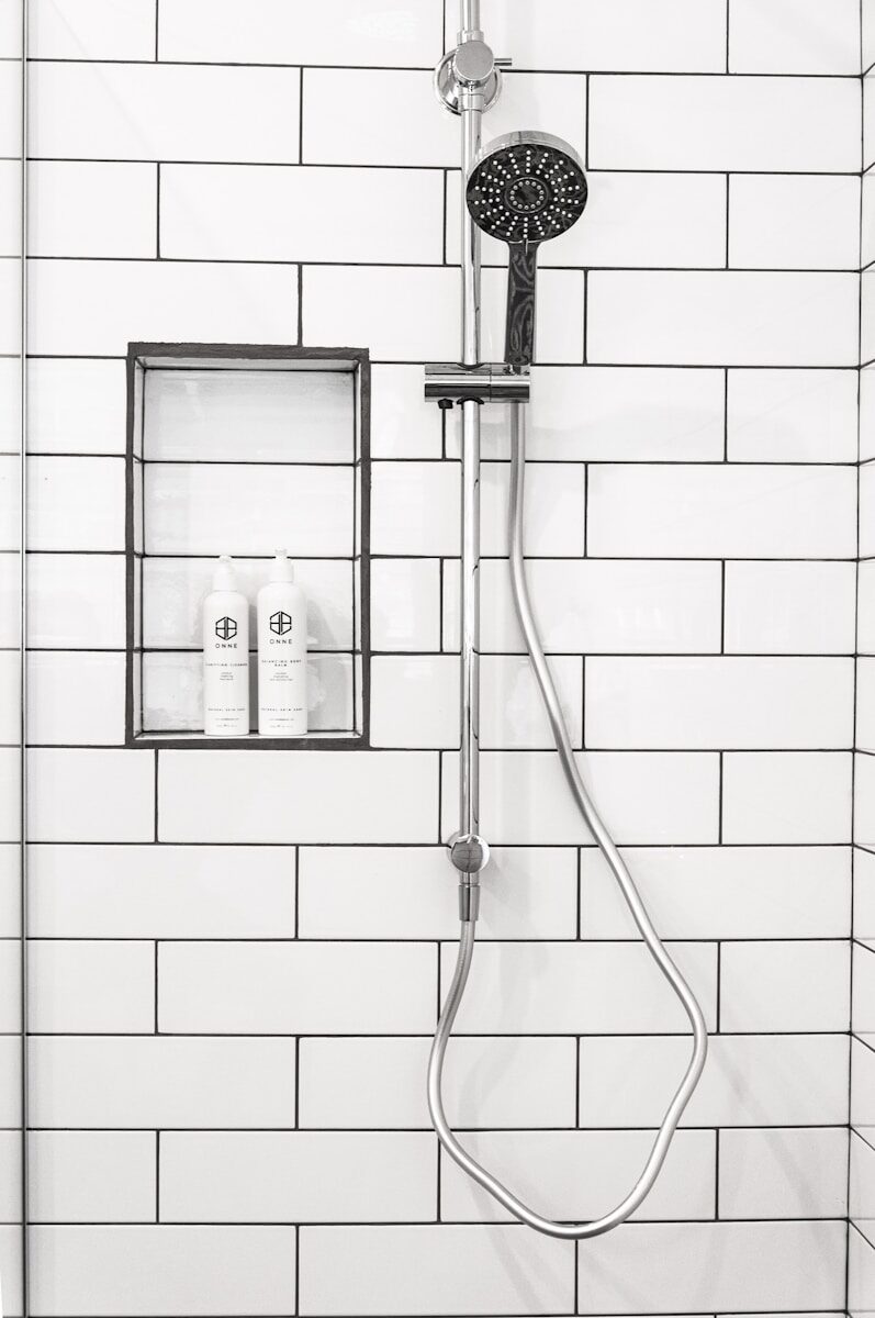silver-colored shower head with white tiles on wall