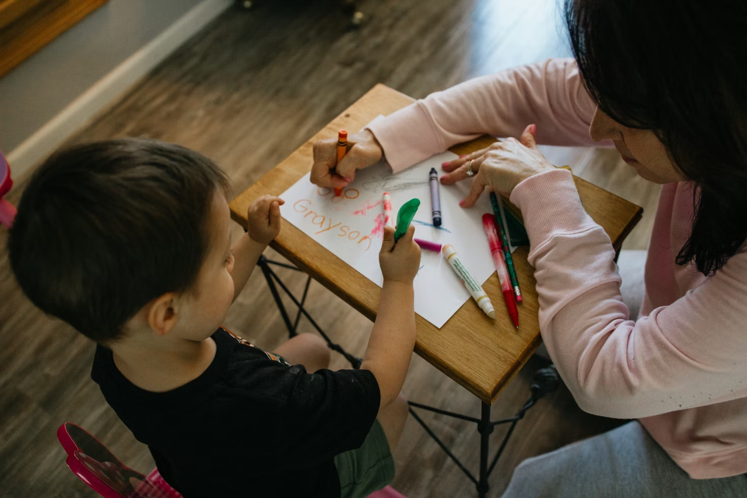 woman and child sitting at table colouring