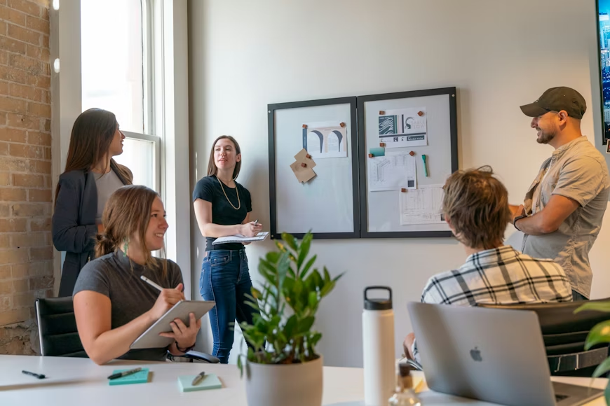 people standing and sitting around an office during a business meeting