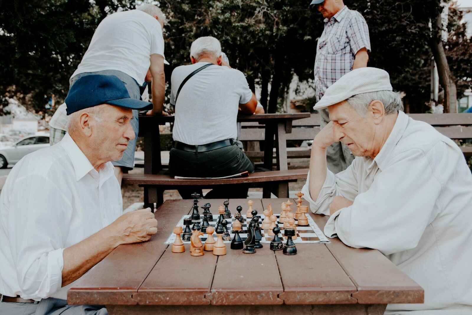 two men playing chess at a picnic table outside