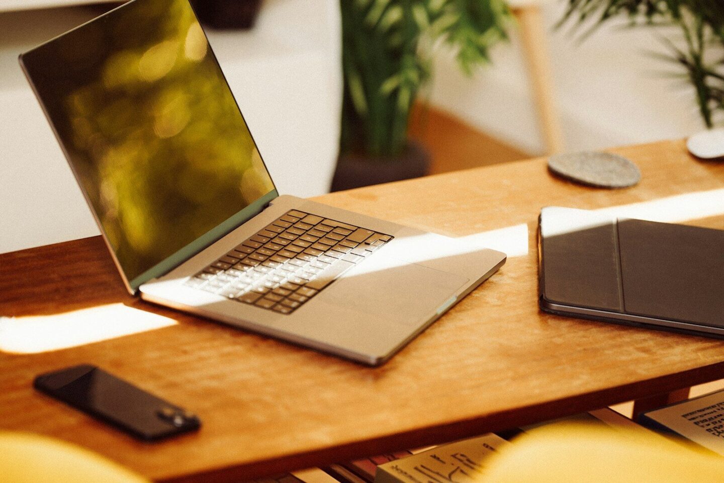A laptop computer sitting on top of a wooden desk in sunlight
