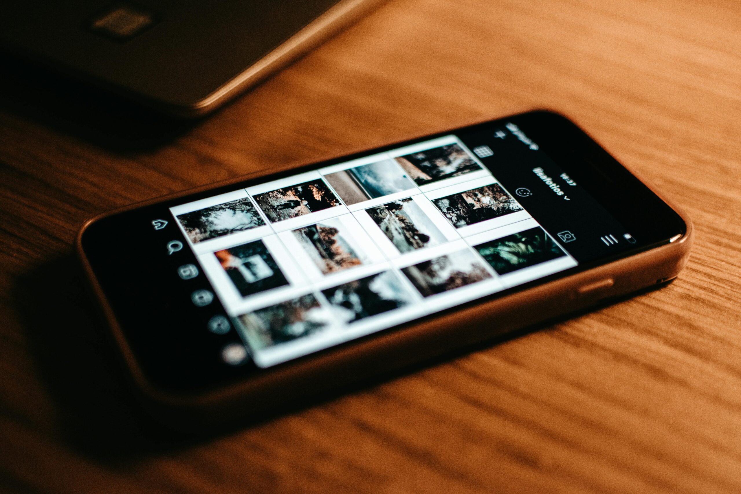 phone on wooden table with screen showing photos
