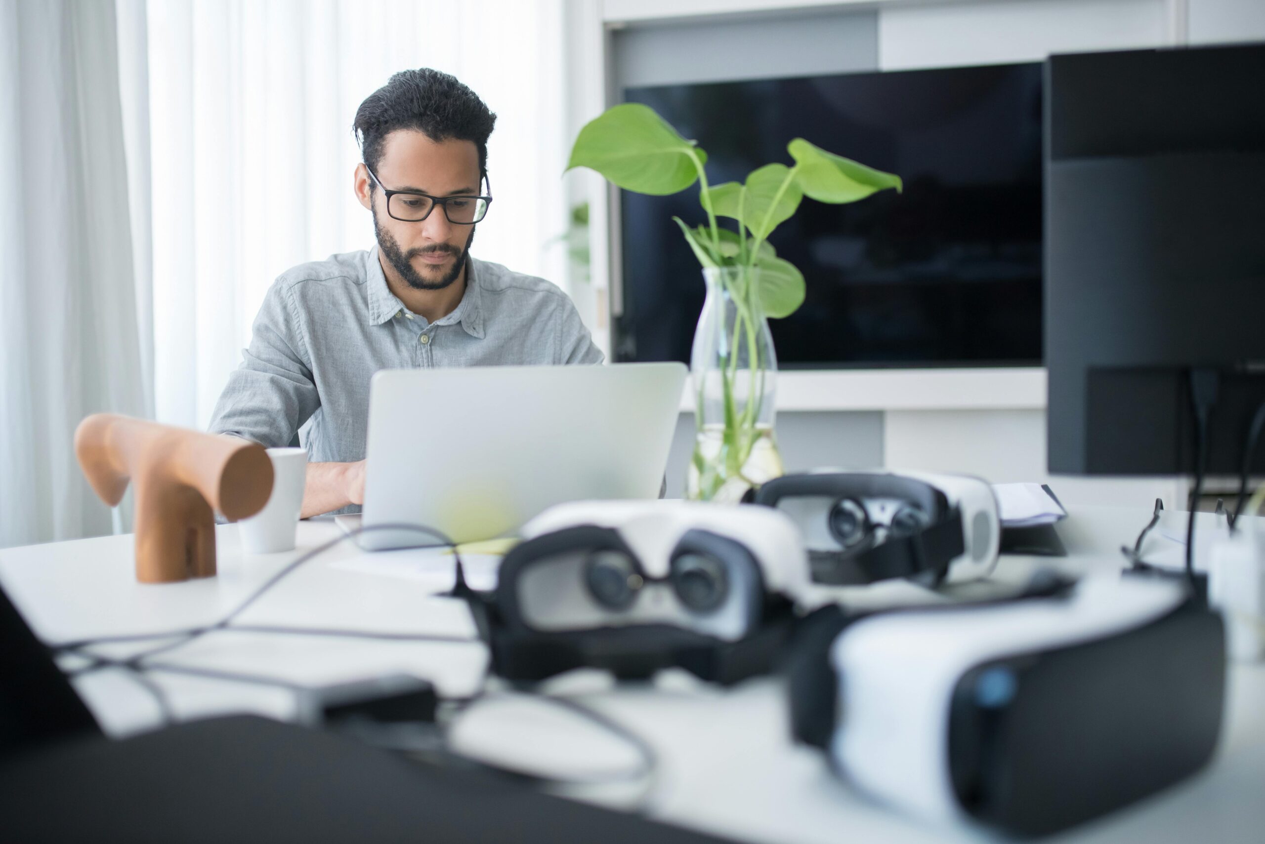 Man in grey shirt and glasses using a laptop