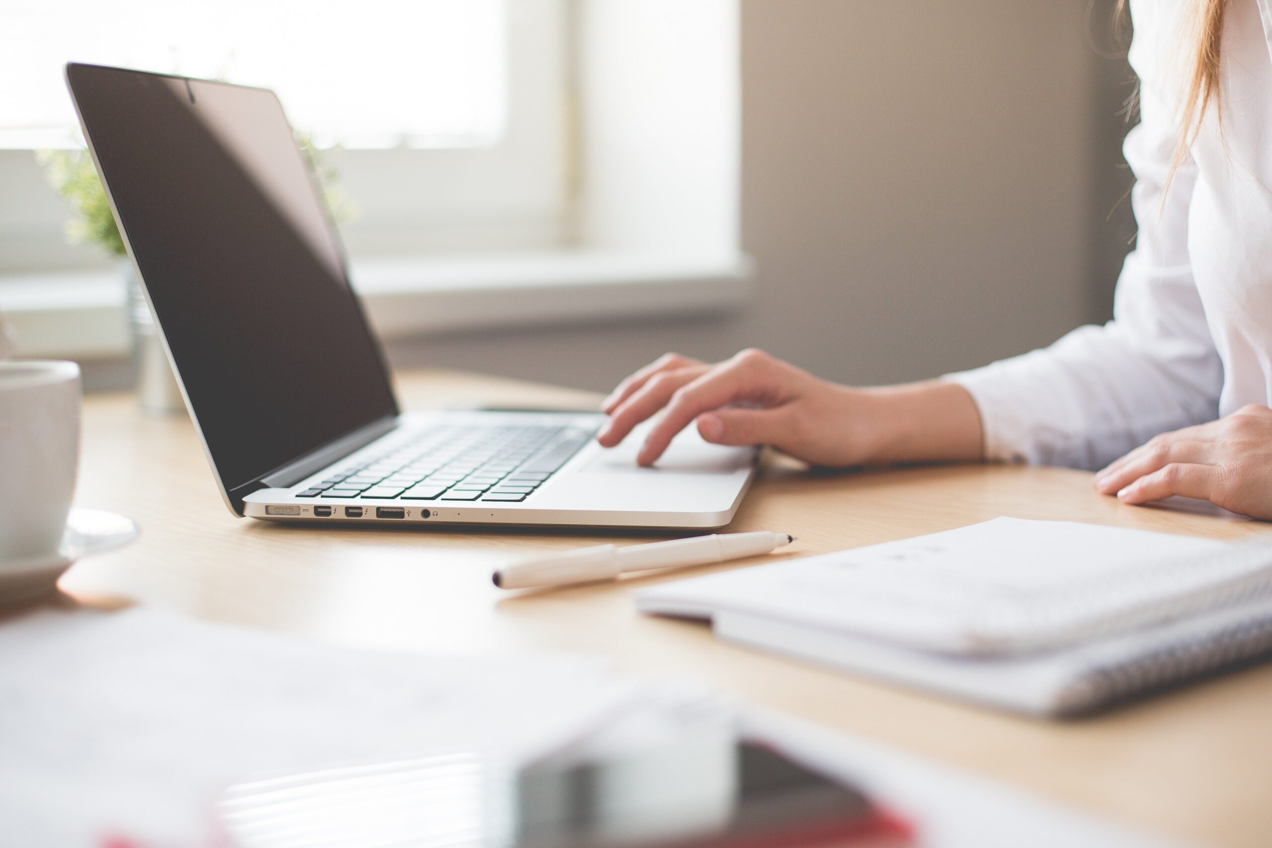 woman's hand typing on laptop on desk