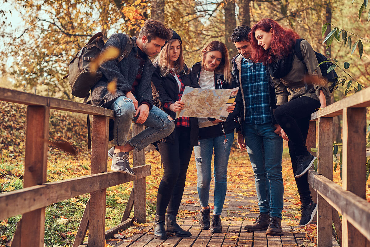 group of young people standing together on bridge outside looking at map