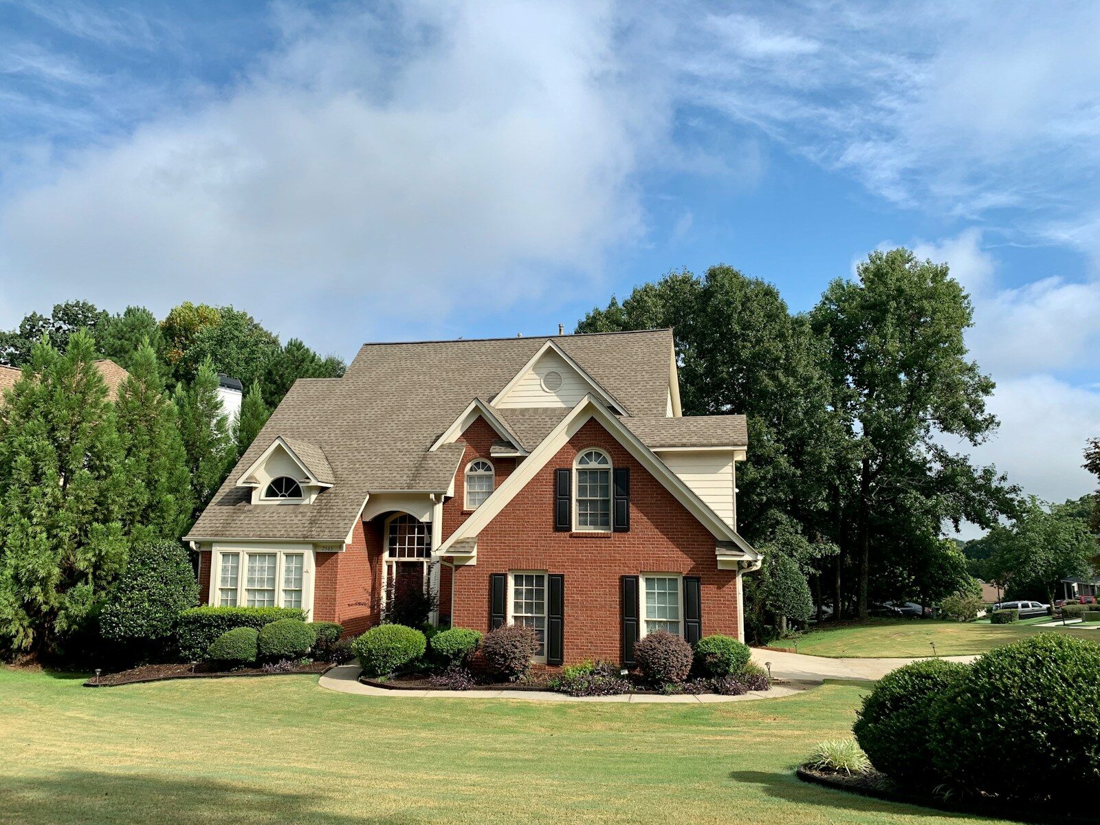 house near green trees under blue sky during daytime
