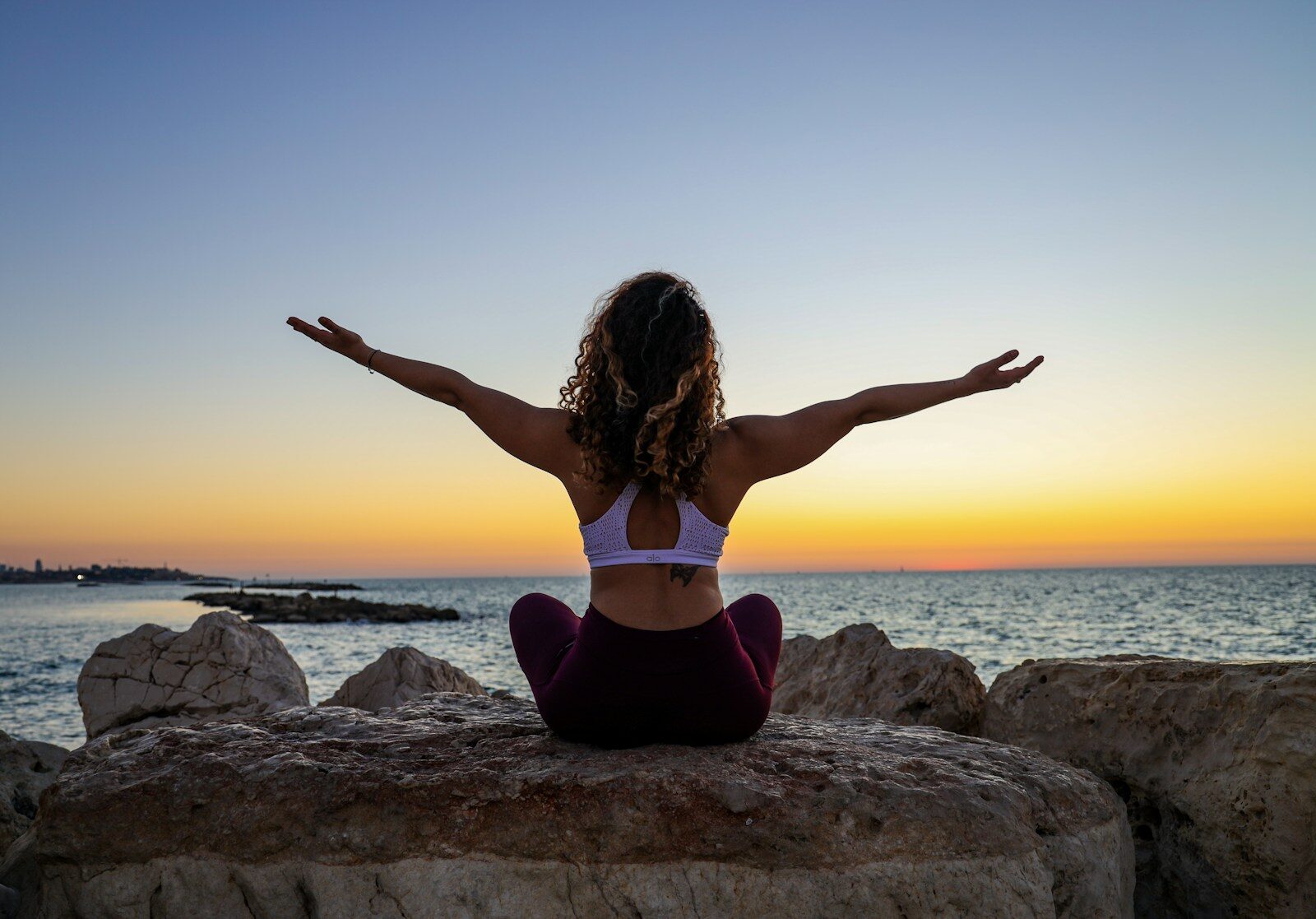 woman sitting on rocks in front of the ocean