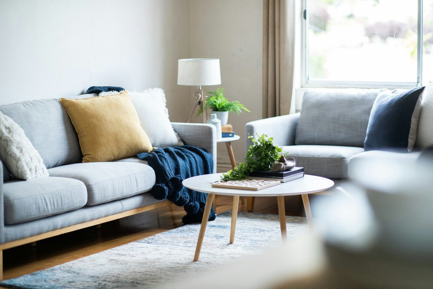 a living room with a sofa and a coffee table, blanket and lamp