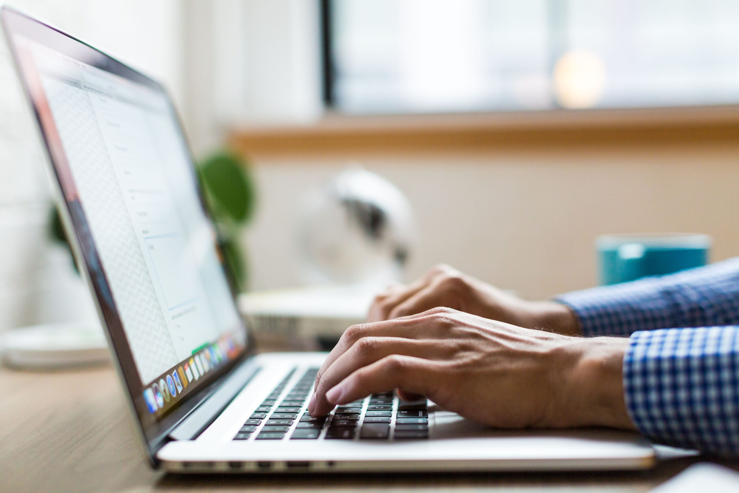 person's hands typing on laptop from the side