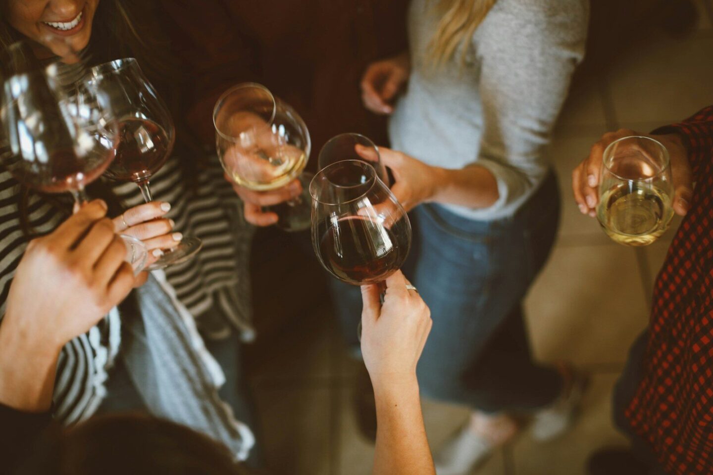 group of people standing up, cheers-ing with glasses of wine