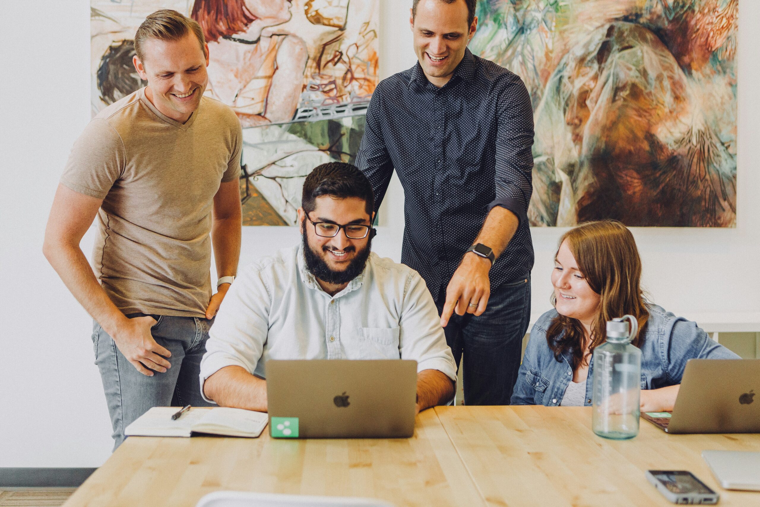 team working together around laptop and laughing