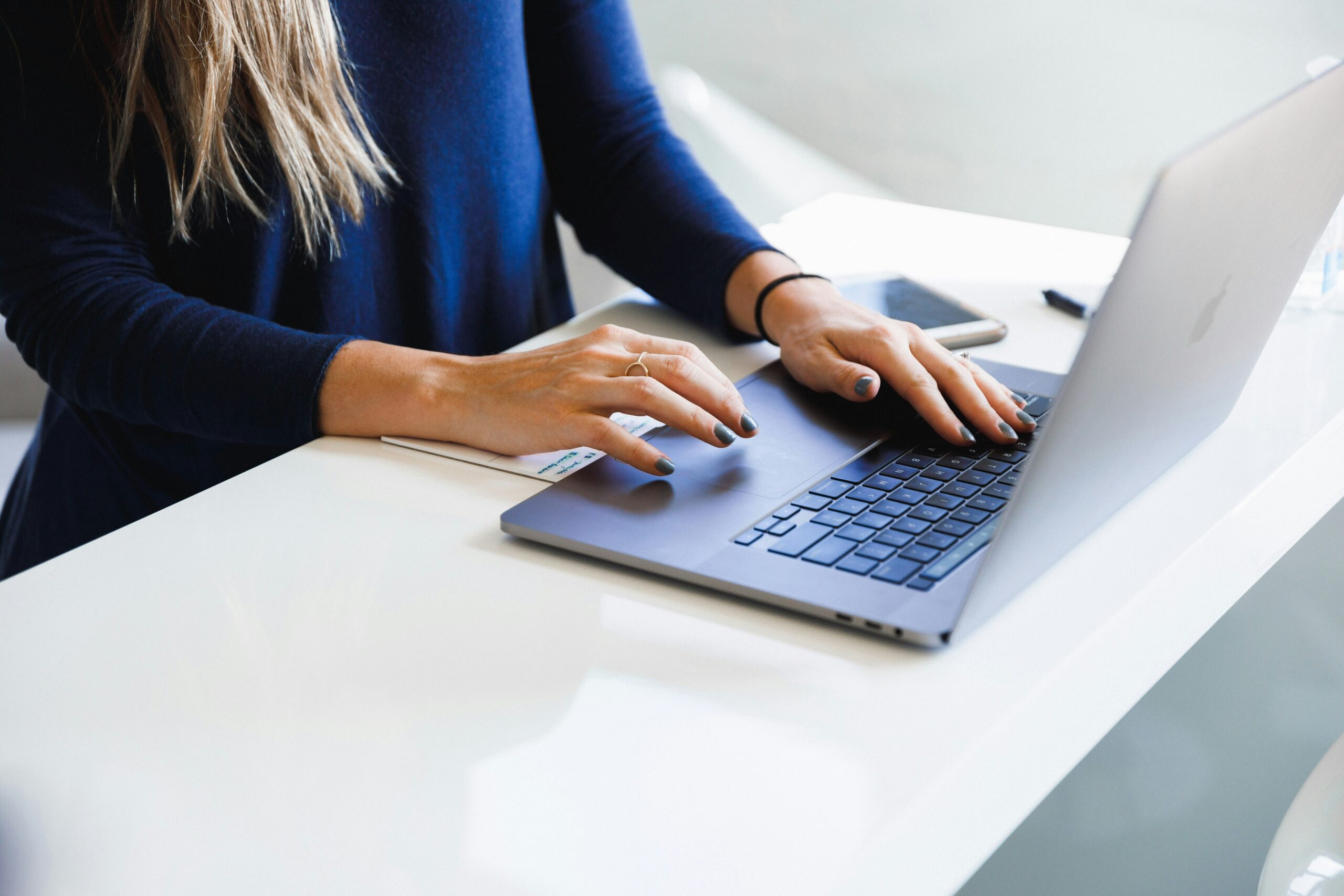woman sitting at desk and typing on laptop