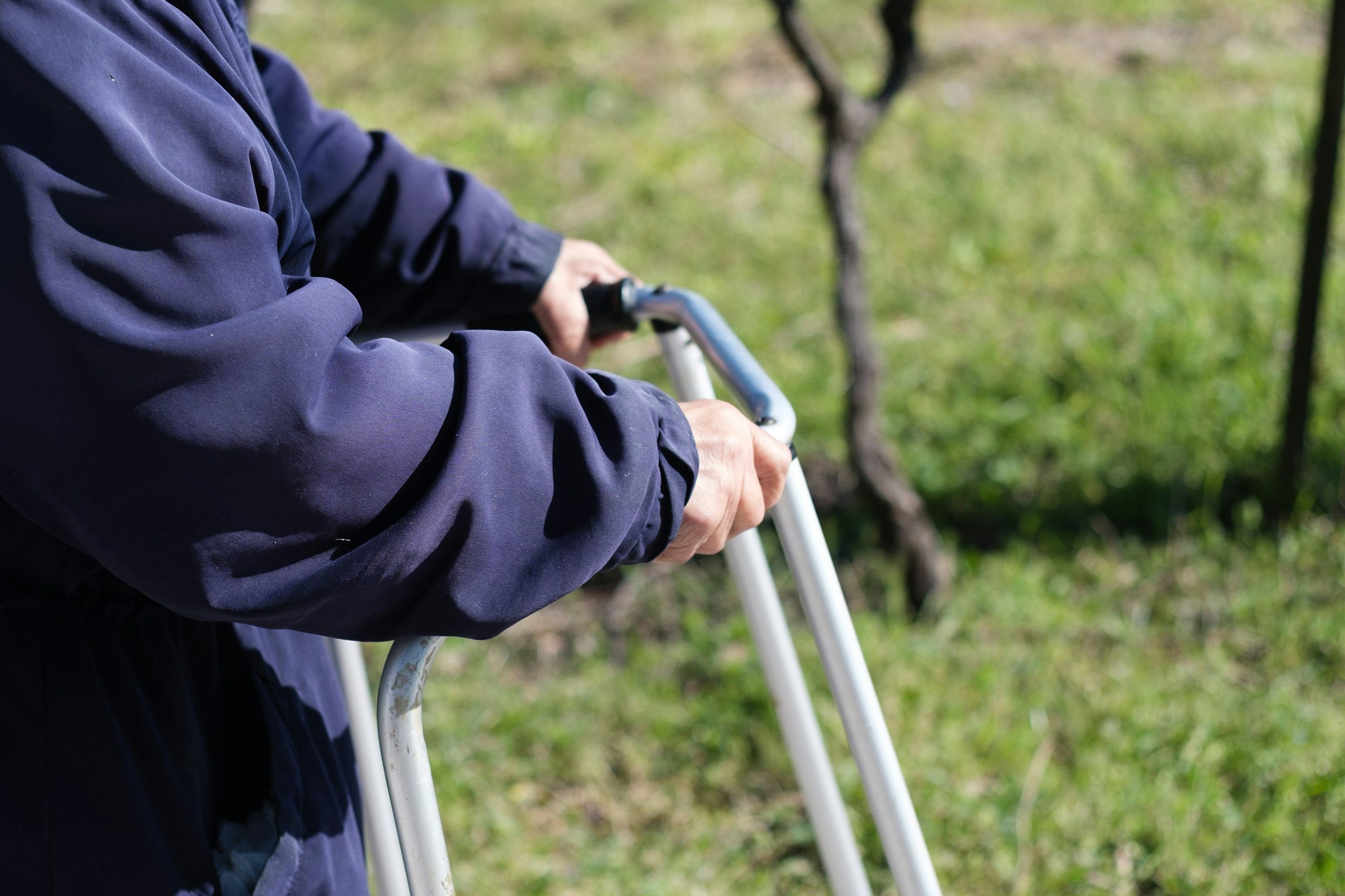 older person holding a walking aid outside