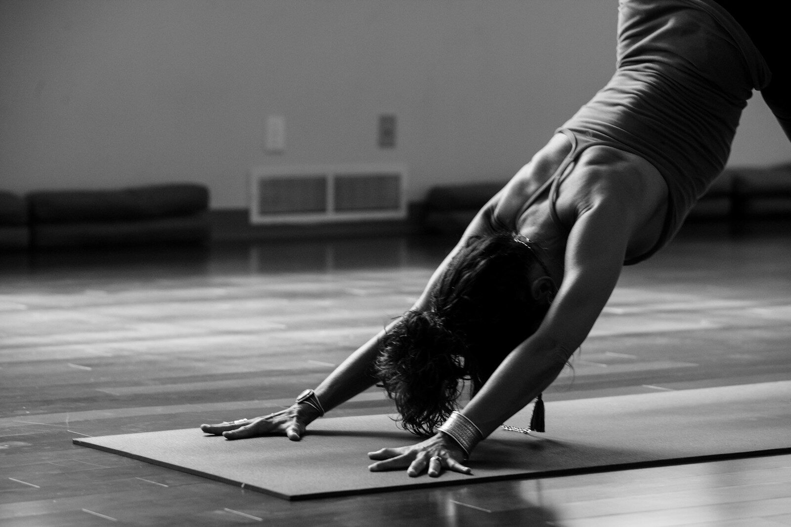 woman in black tank top and black trousers doing yoga on mat on floor