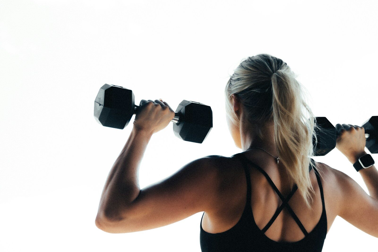 A woman holding two dumbbells in her hands