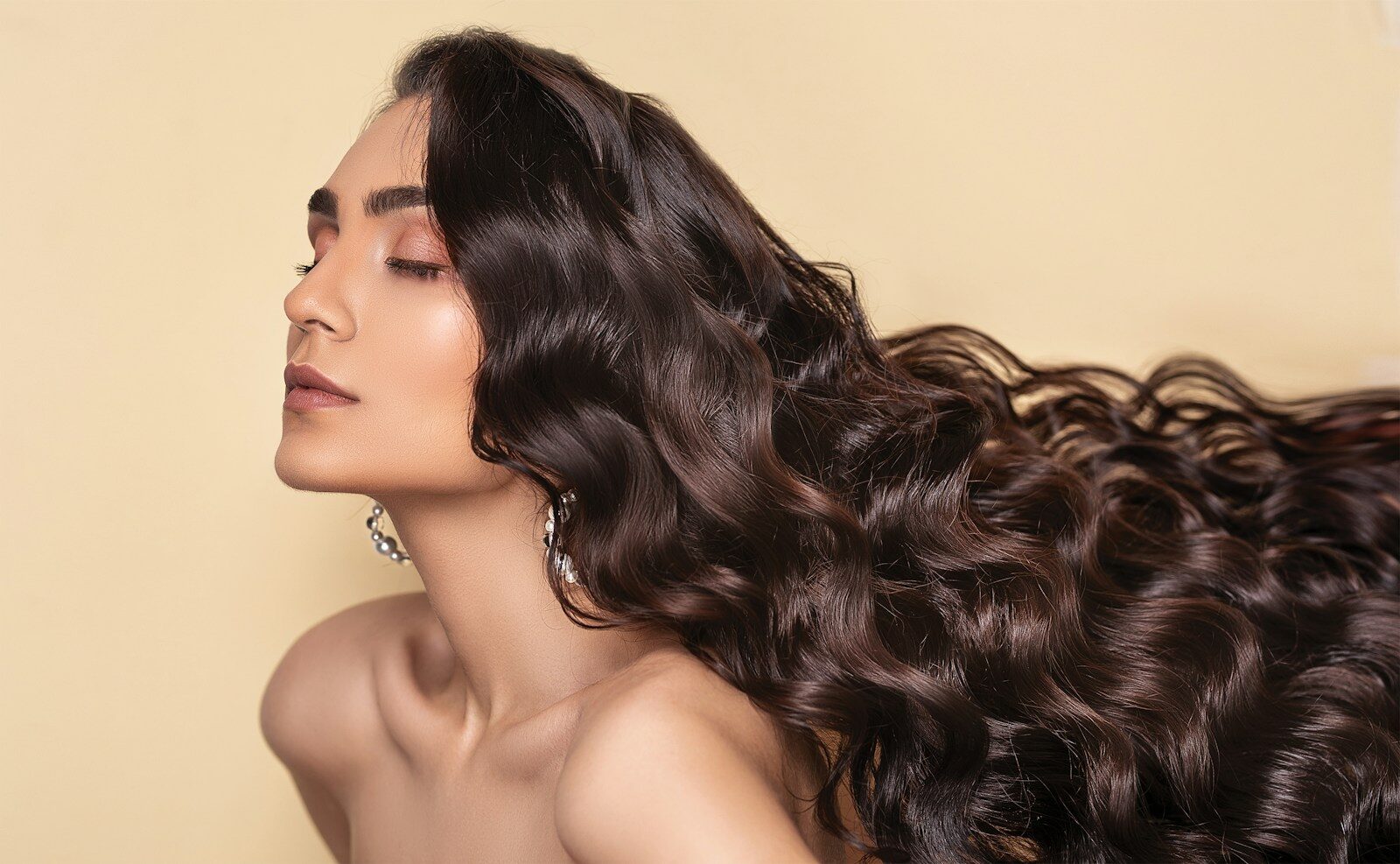 woman with eyes closed and long brown hair flowing behind her