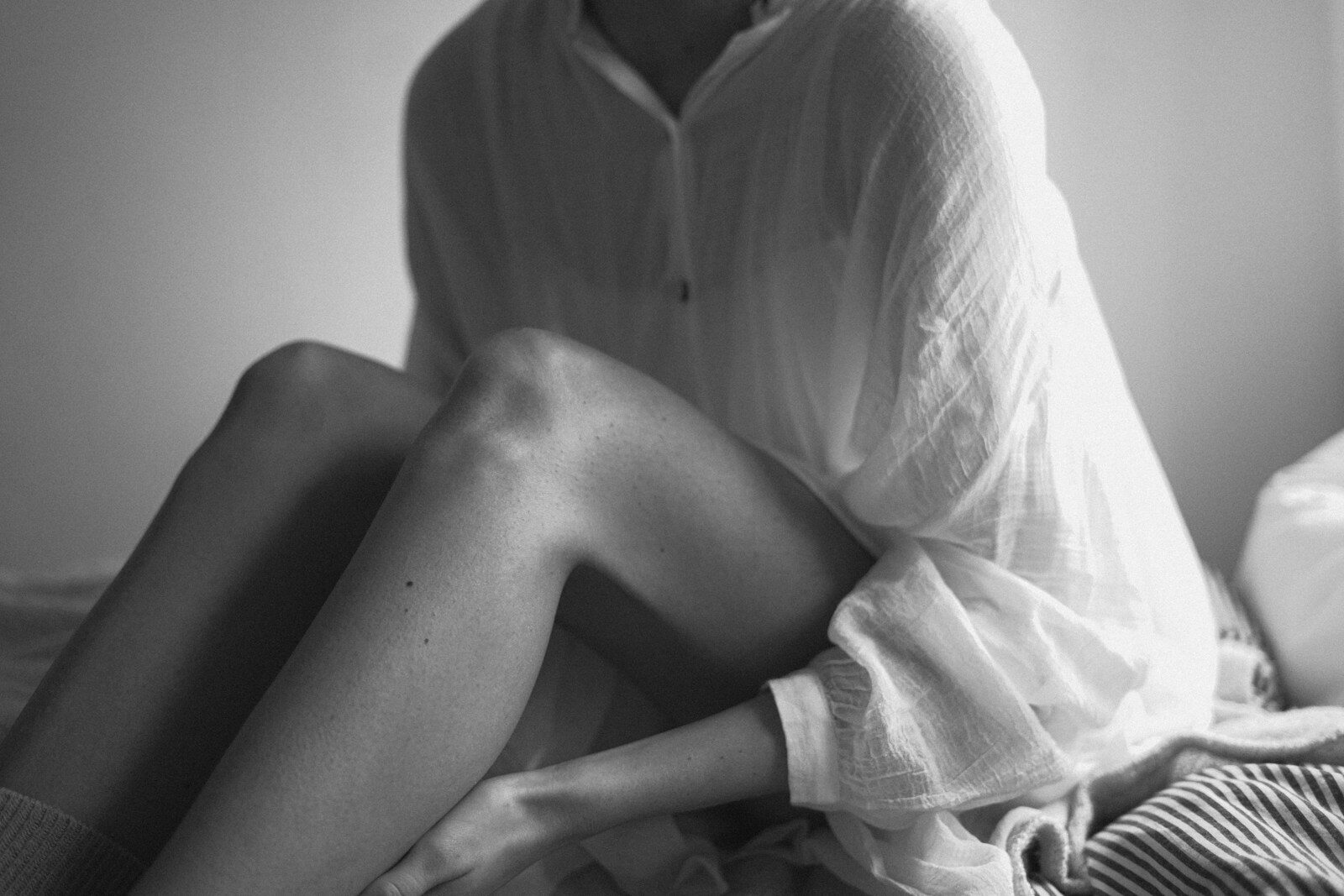 woman sitting up on bed wearing white shirt