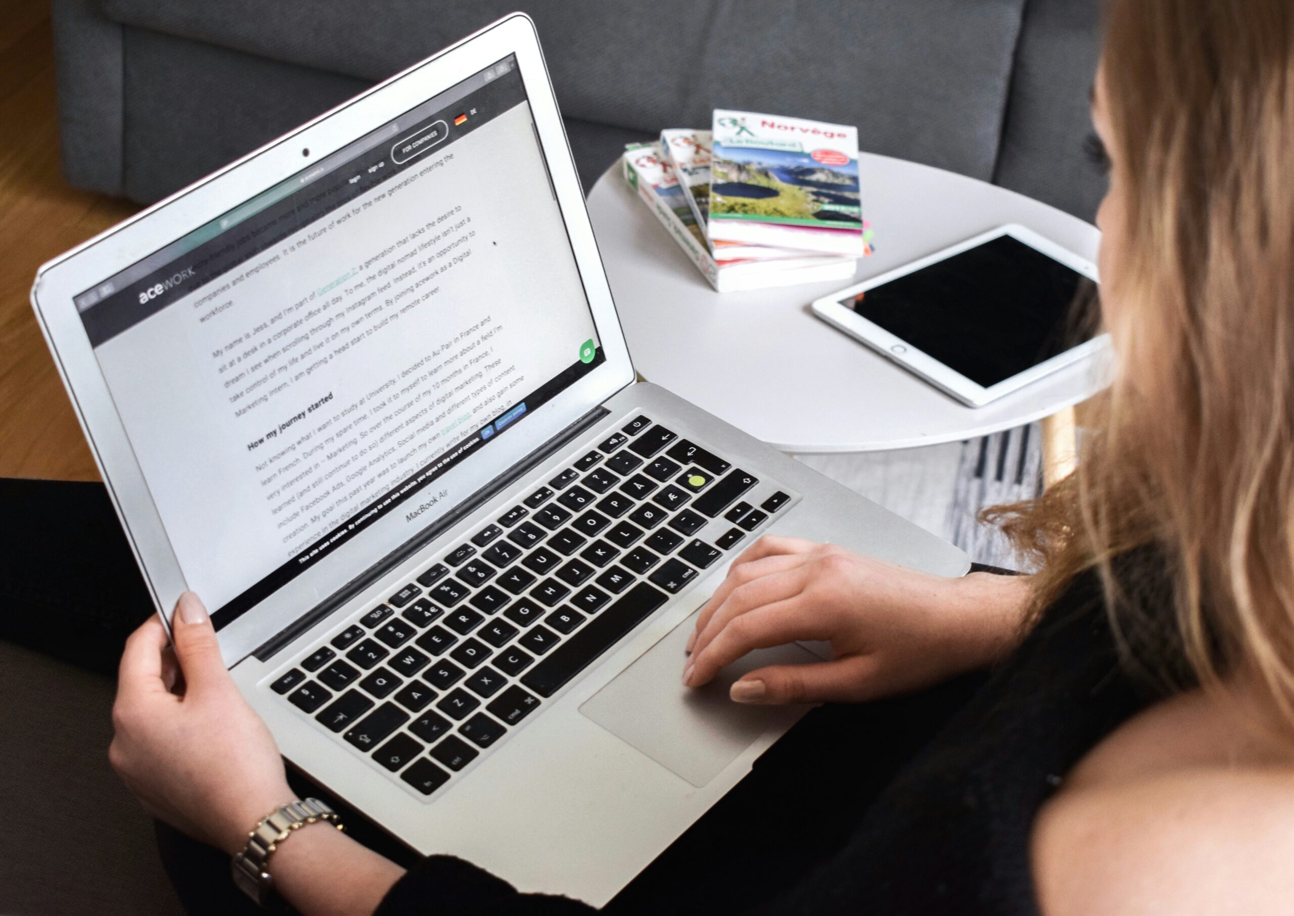 woman sitting down with laptop on her knee next to table