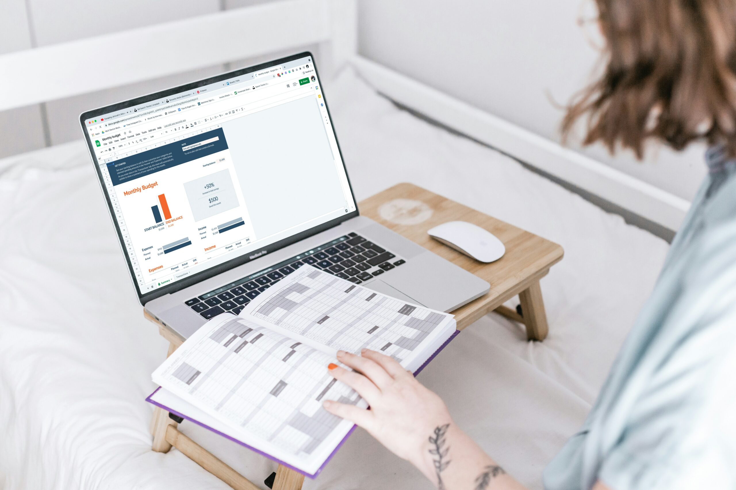 woman sitting with laptop in front of her on pop-up table and a diary open on it