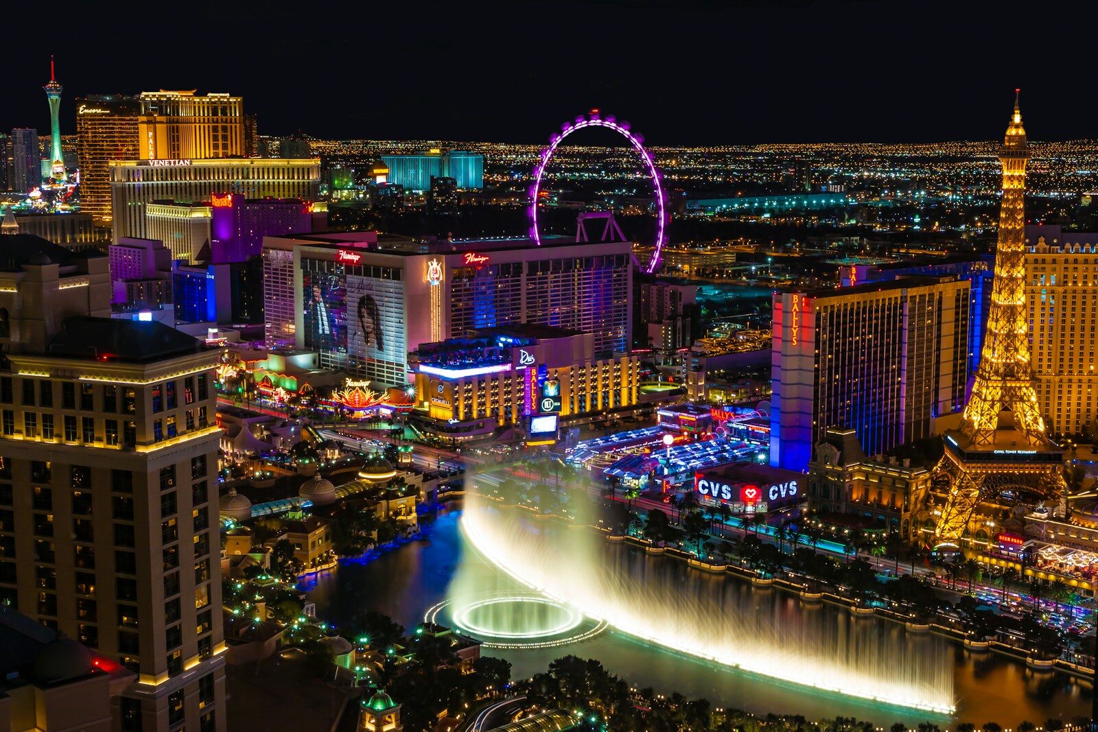 view of las vegas from high up with bright lights and big wheel at night