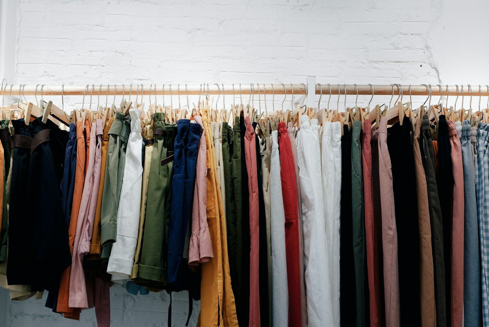 lots of clothes hanging on wooden clothes rail